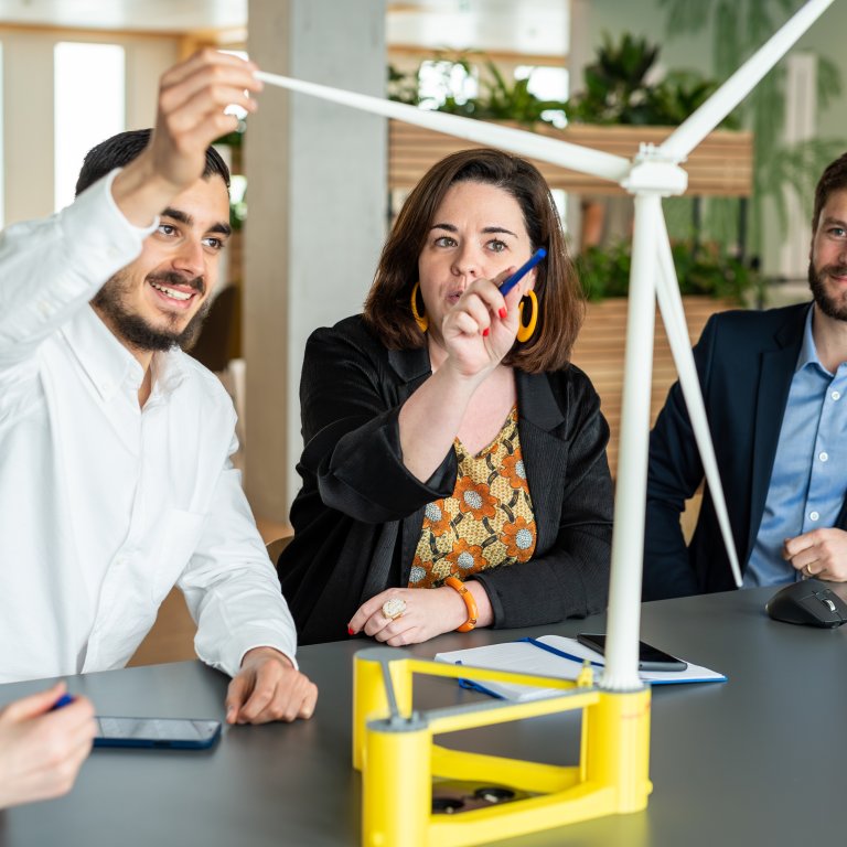 Technip Energies employees interacting with a 3D model of a wind turbine