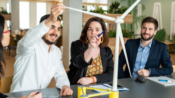 Technip Energies employees interacting with a 3D model of a wind turbine