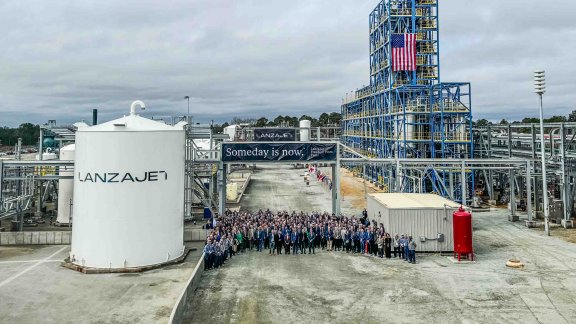 Image of people standing in front of a huge industrial plant site