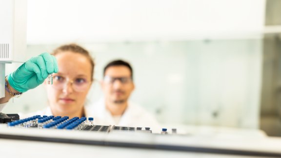 Two scientists from Technip Energies, one of them is holding and inspecting a flask