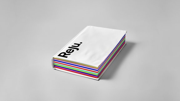 A notebook with Reju branding (logo, white cover, and colorful pages in various hues, visible along the edges)